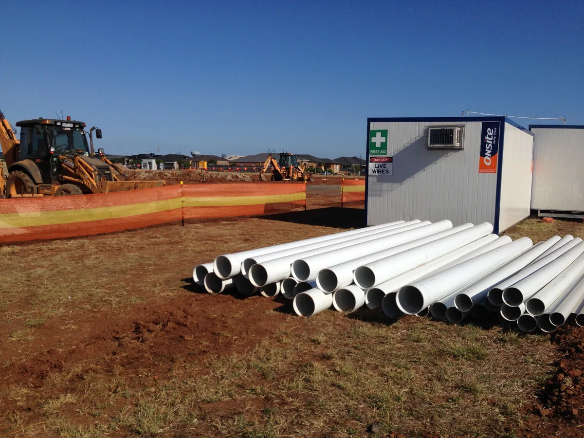 Lengths of white drainage pipe stacked on a construction site