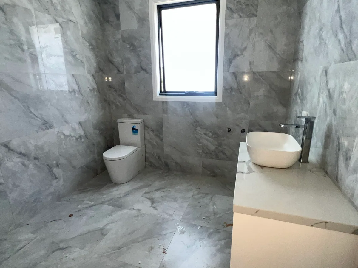White toilet and vessel basin with a chrome mixer in a grey tiled bathroom